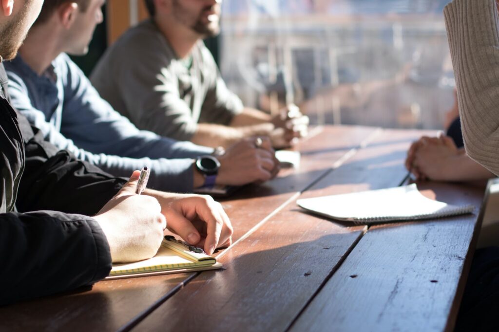 People sitting at a wooden table, writing notes, to represent psychographics