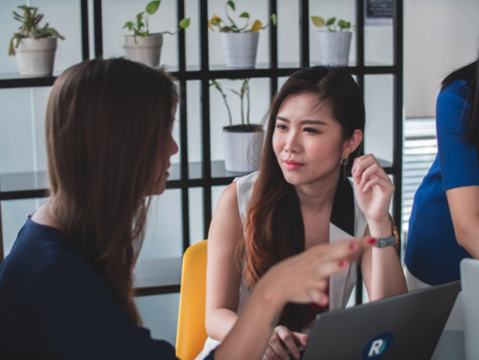 Two women speaking to each other, one listening intently. 