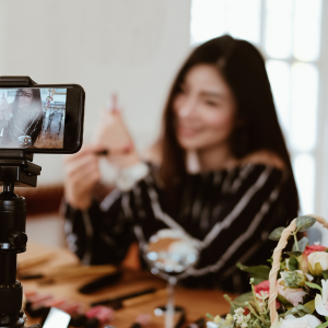A woman, social media influencer, recording herself with an iphone on a tripod inside of a restaurant.